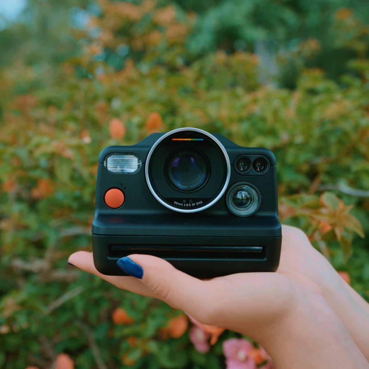 Polaroid I-2 Camera Review | Hand holding camera next to flowers.